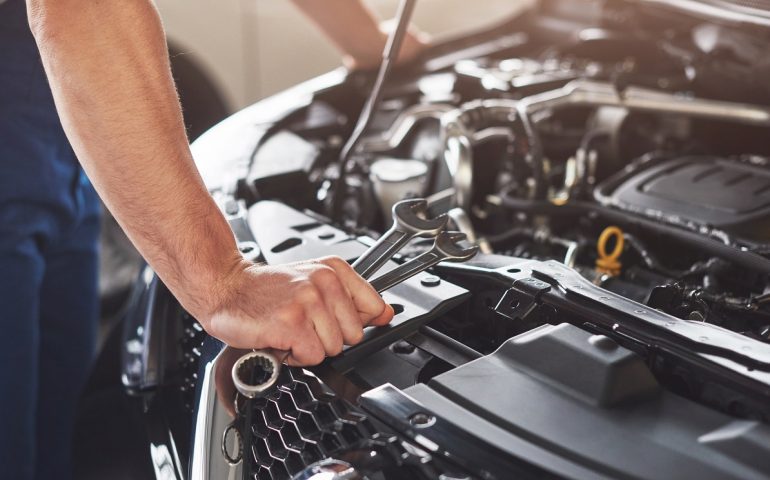 muscular car service worker repairing vehicle