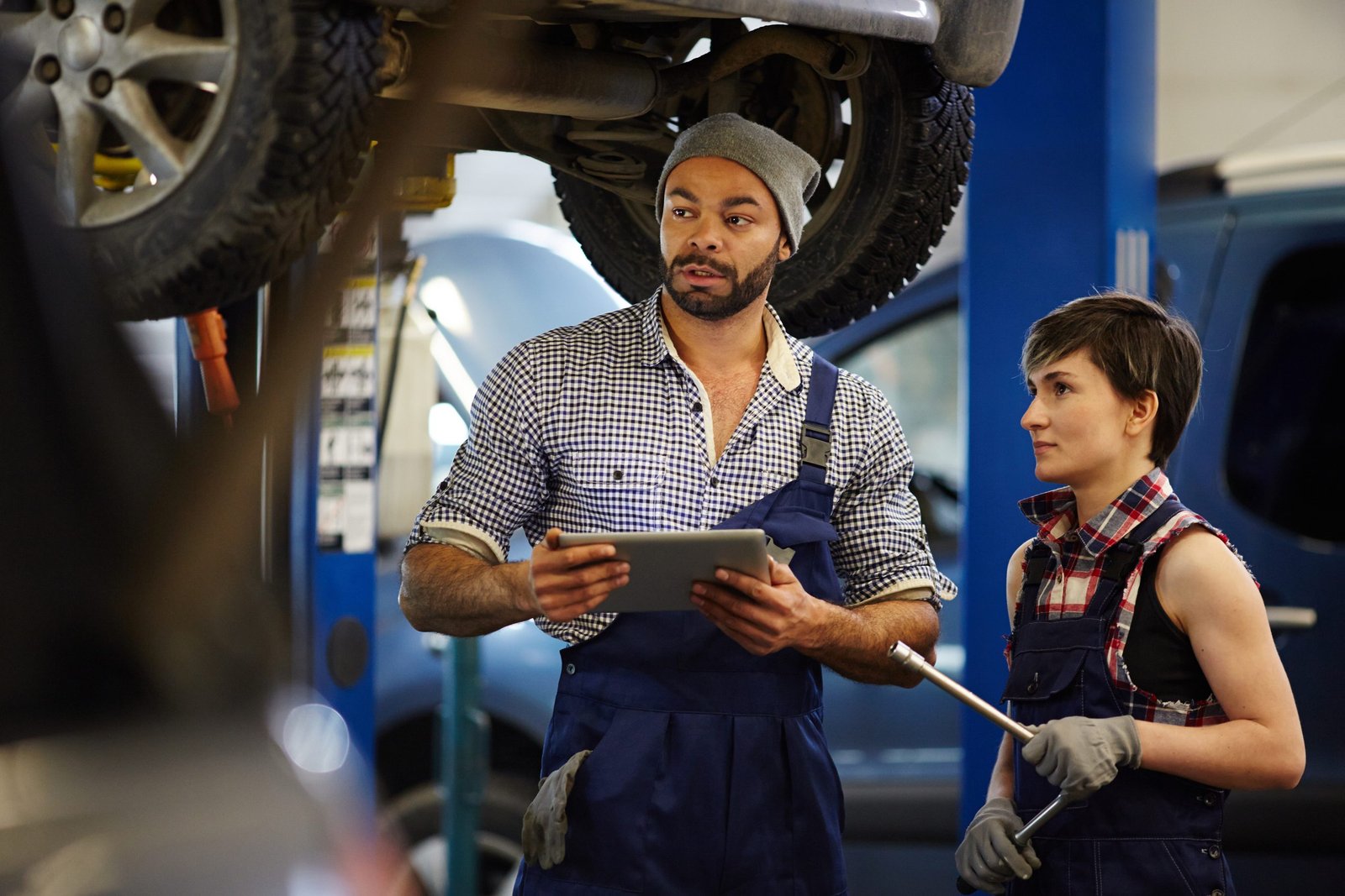 Repair mentor consulting his trainee in garage